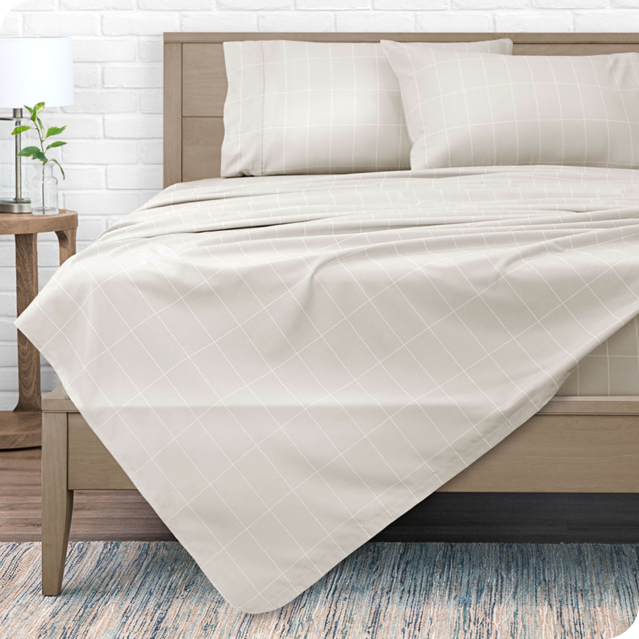 A modern bed with a microfiber sheet set on it.