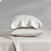 Two pillows with pillowcases on them stacked on a bed