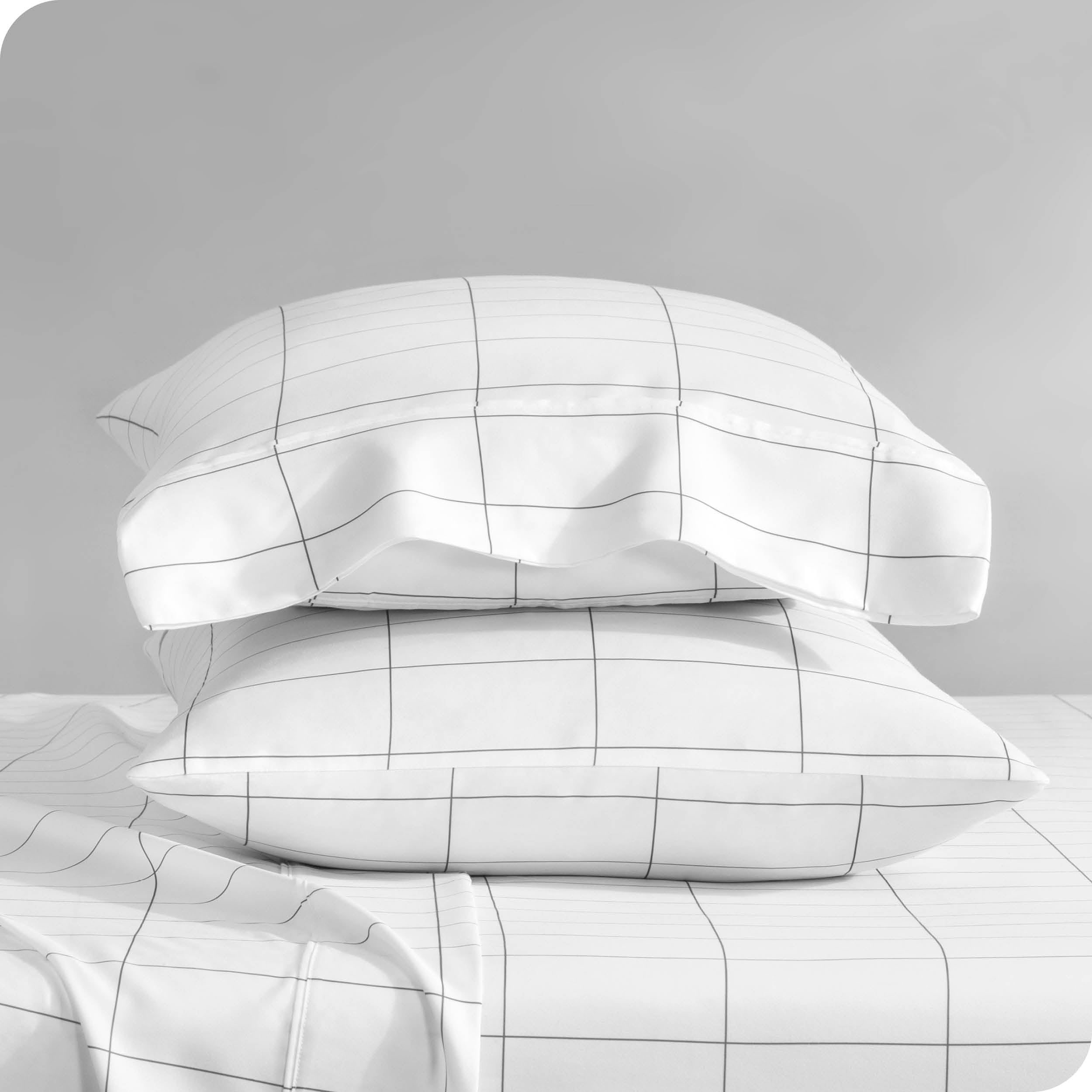 Two pillowcases on pillows stacked on a bed with matching sheets