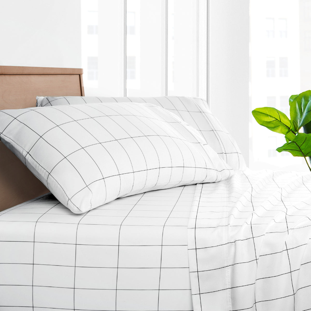 Grid-patterned bedding set on a bed with a wooden headboard and green plant.