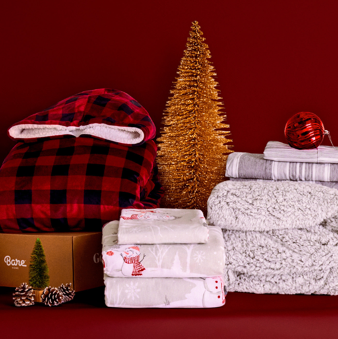 Duvets, sheet sets, blankets and other giftable items on a red background with holiday bows. 