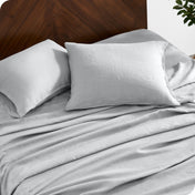 Close up of linen sheet set on a mattress with pillows inside the pillowcases