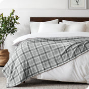 Bed with plaid blanket and white pillows in a bedroom setting