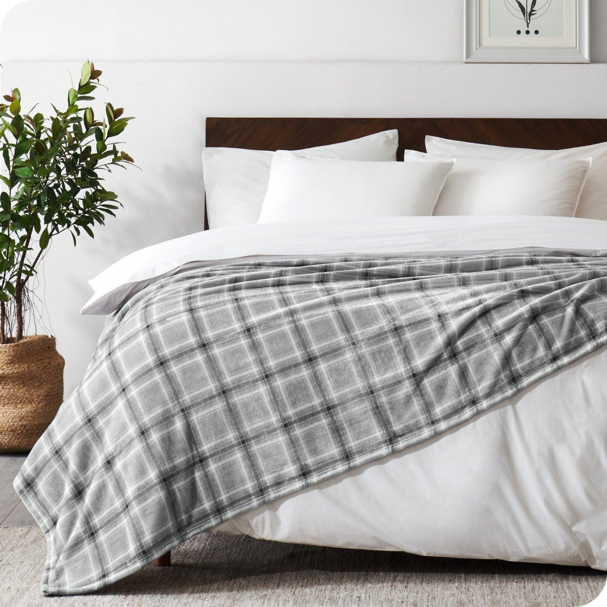 Bed with plaid blanket and white pillows in a bedroom setting