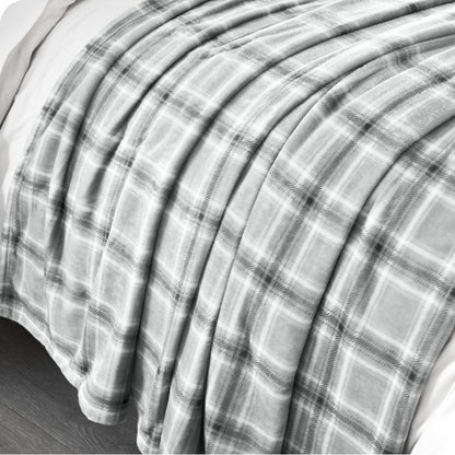 Plaid blanket draped over a bed with a neutral background