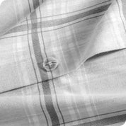 Close-up of a gray plaid duvet with a button