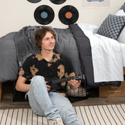 Person sitting on a bed holding a guitar in a bedroom setting with vinyl records on the wall.