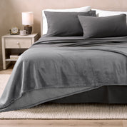 Bed with grey sheets and a sherpa blanket