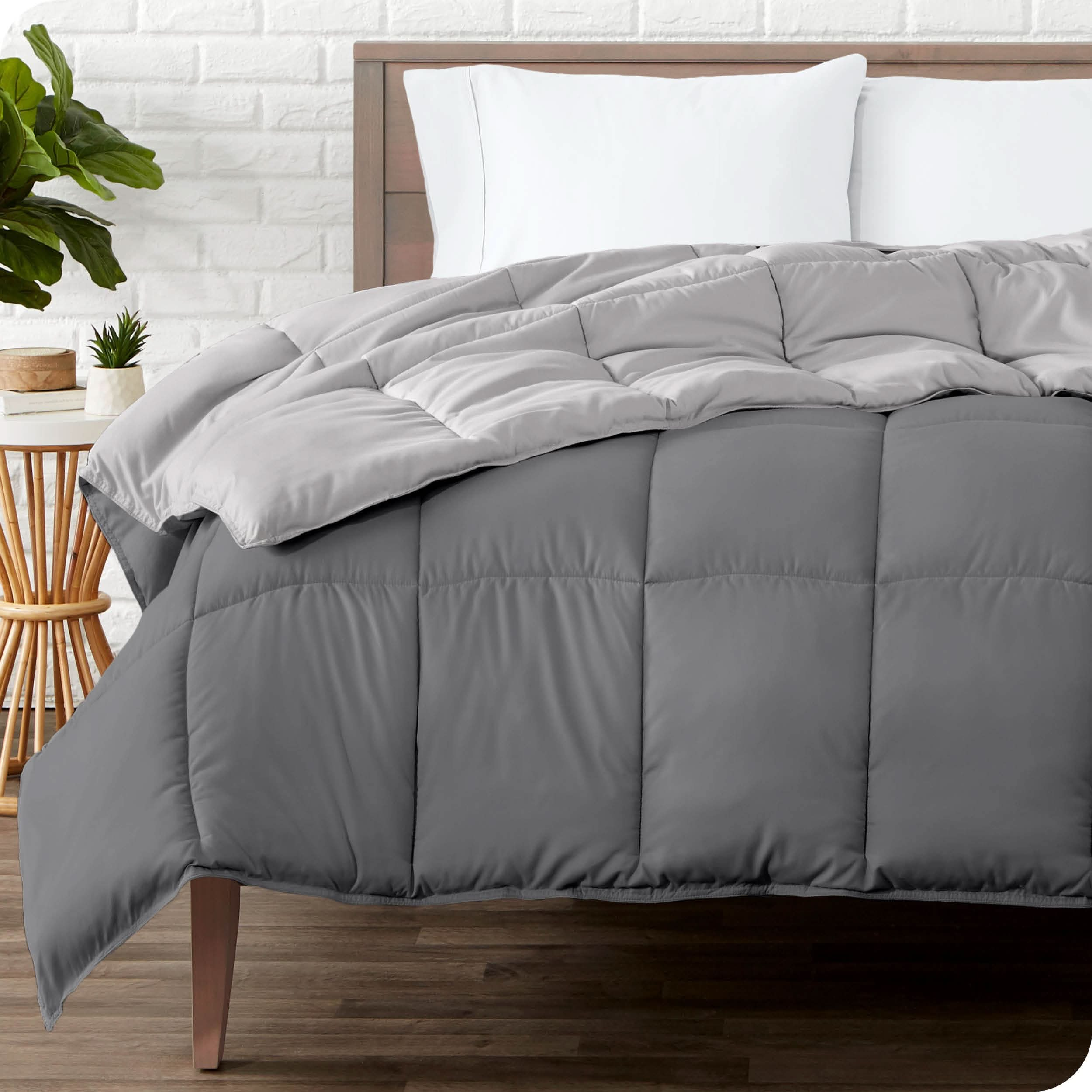 Wooden bed frame with a reversible comforter on the mattress. The comforter is folded back showing the two different colored sides.