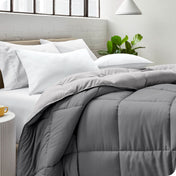 Close up of a comforter on a bed folded over itself. There are also 4 pillows on the bed.