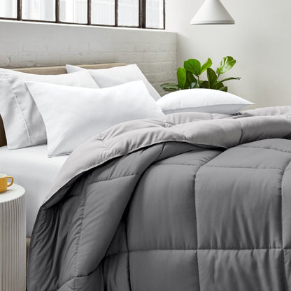 Bed with comforter and white pillows in a bright bedroom setting.
