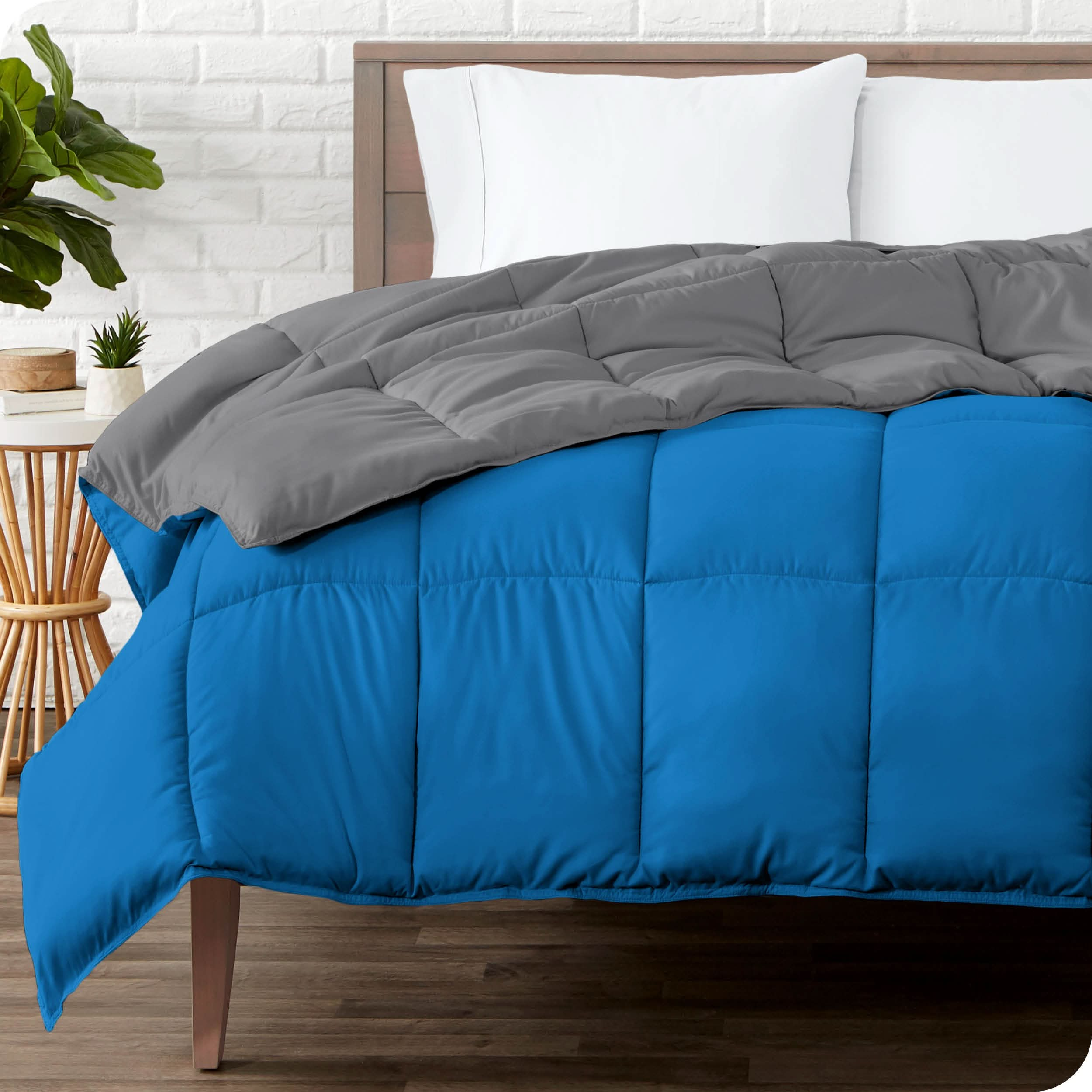 Wooden bed frame with a reversible comforter on the mattress. The comforter is folded back showing the two different colored sides.