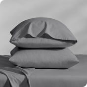 Pillows inside percale pillowcases stacked on a bed
