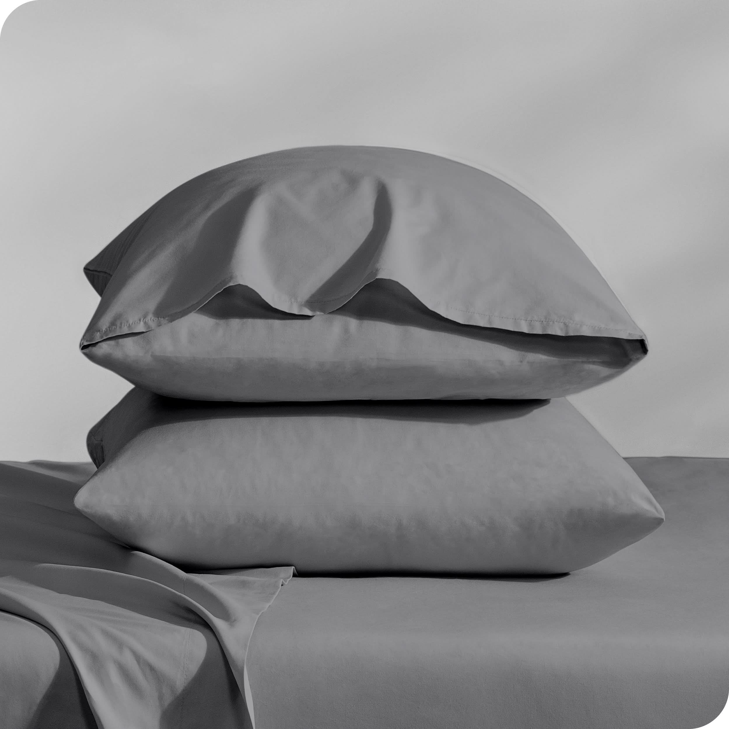 Pillows inside percale pillowcases stacked on a bed
