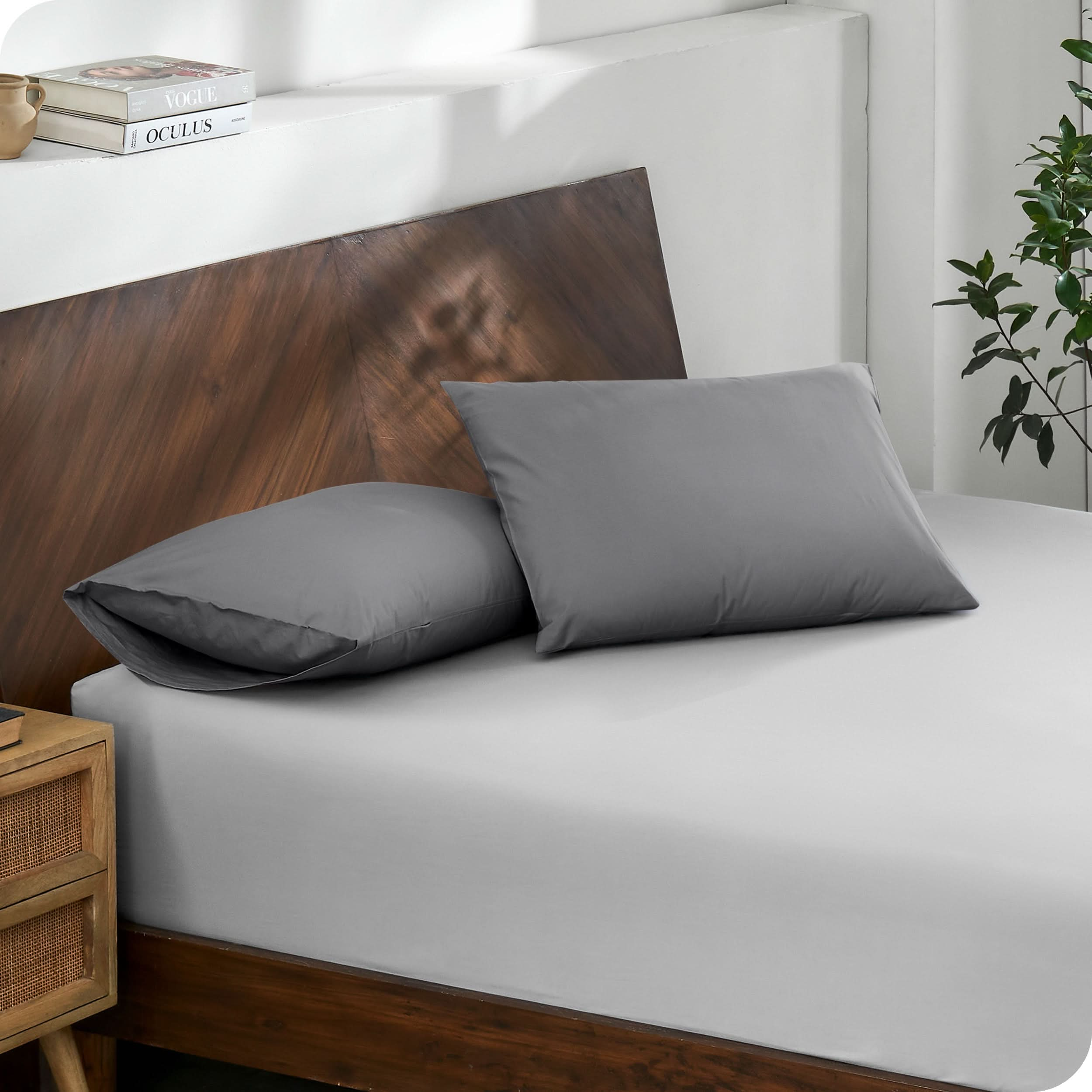 Diagonal view of modern wood bed with a fitted sheet and pillowcases

