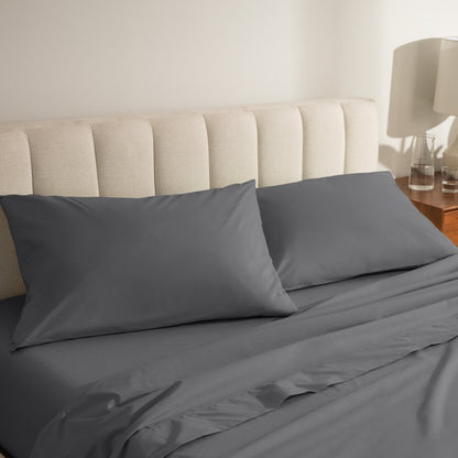 Percale bed sheets and pillowcases on a neatly made bed with a beige headboard.
