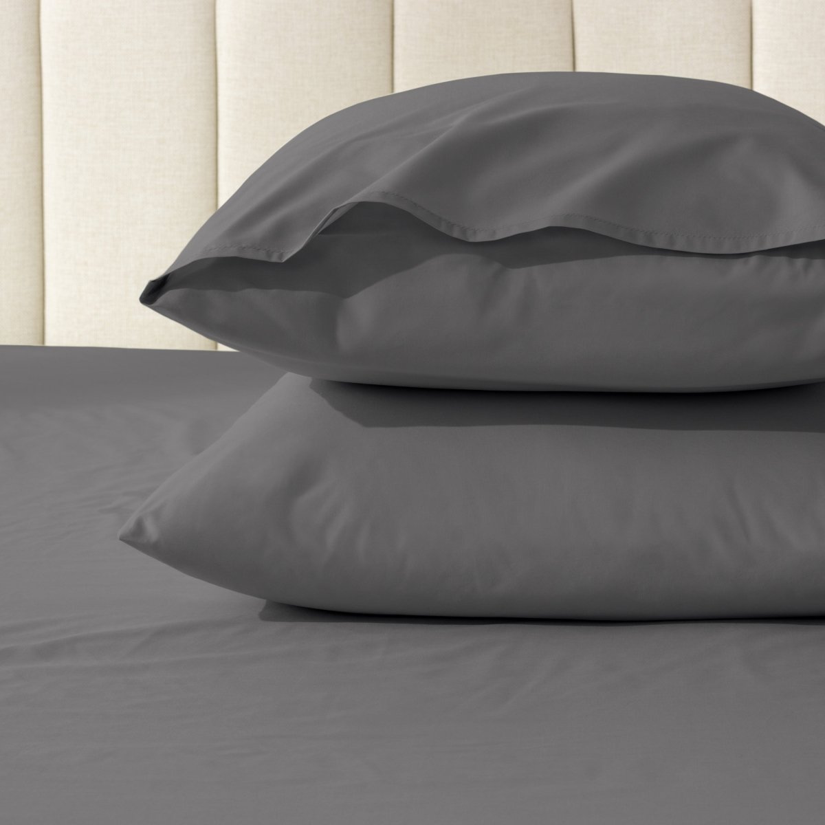 Two pillows stacked on a bed with percale pillowcases on them