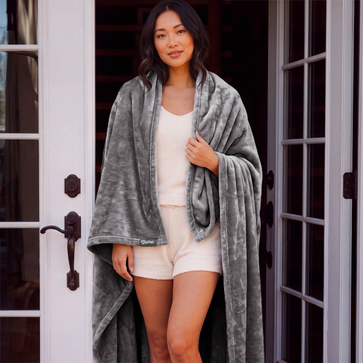 A woman standing with a microplush blanket wrapped around her