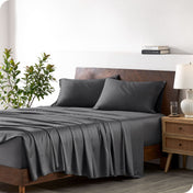 A bamboo sheet set draped over a bed with a wooden bed frame