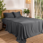 Bamboo sheets on a bed in a bedroom with plants and a lamp.