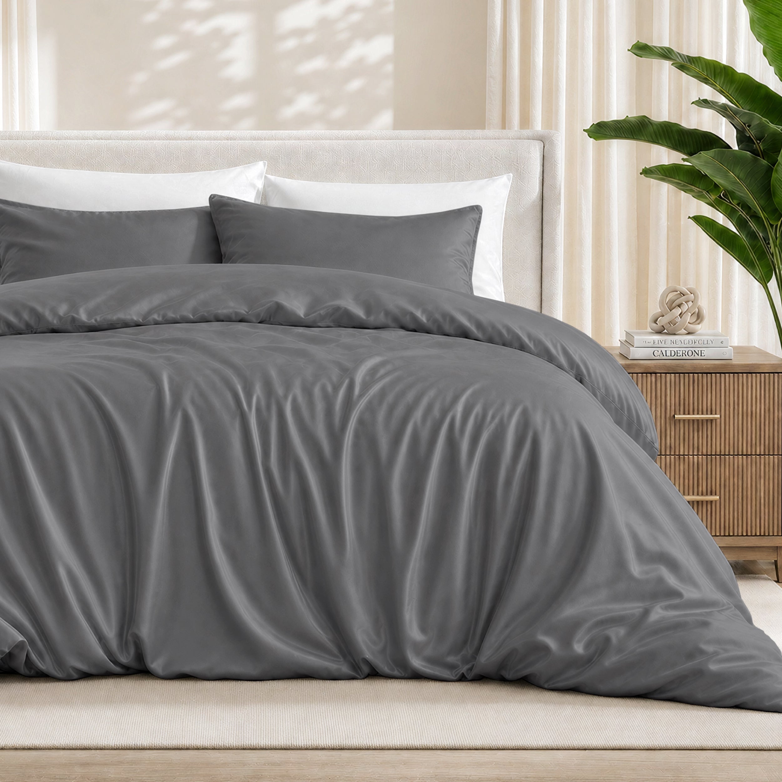 Grey duvet cover set on a bed in a bedroom setting with a plant and nightstand.