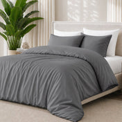Grey bedding set on a bed with a plant in the background