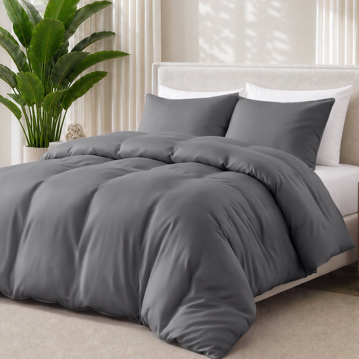 Grey bedding set on a bed with a plant in the background