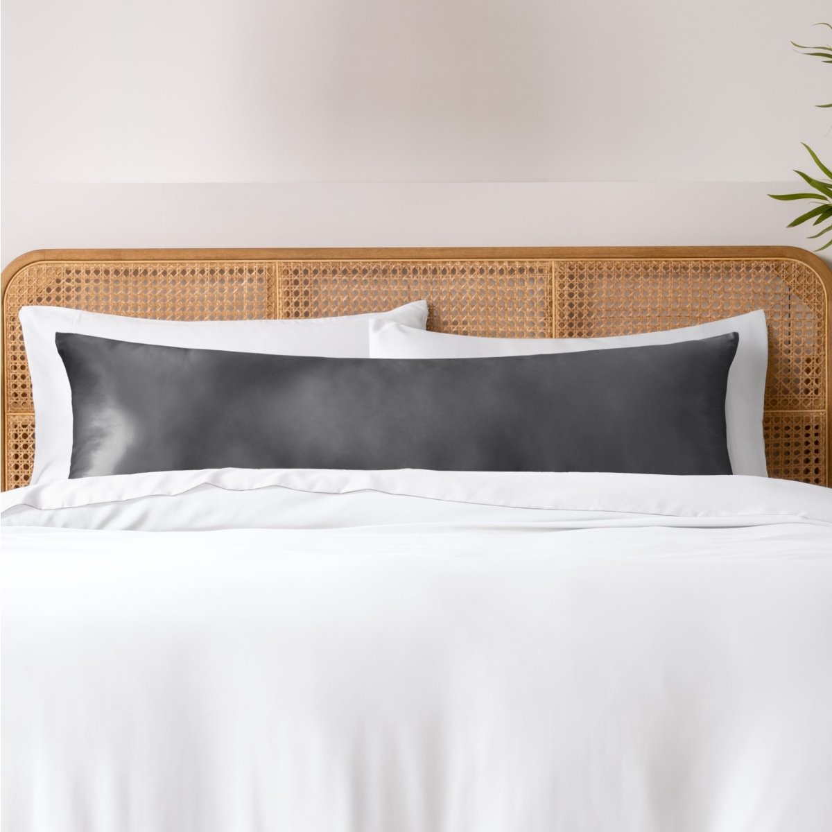 Pillows, sheets and a duvet cover on a bed with a wicker headboard and light gray bedding.