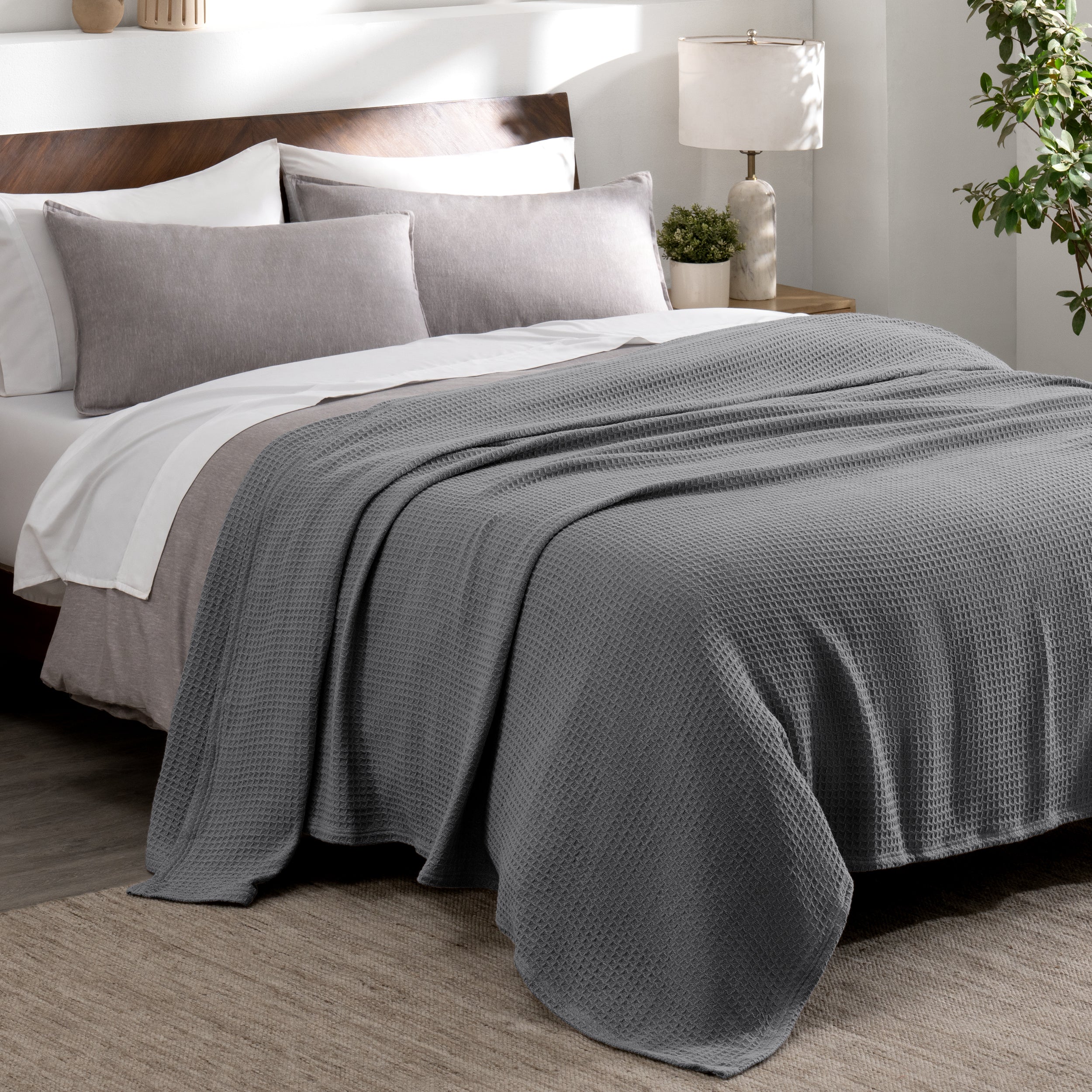 Cotton waffle blanket draped over a bed with pillows in a bedroom setting.