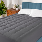 A cotton top mattress pad on a mattress in a modern bedroom.