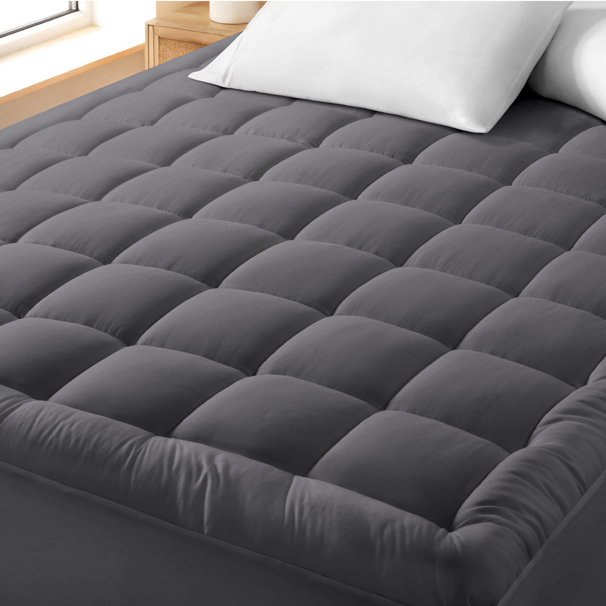 A cotton top mattress pad on a mattress in a modern bedroom.