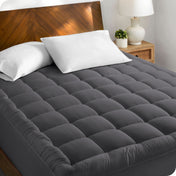 A cotton top mattress pad on a mattress in a modern bedroom.