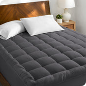 A cotton top mattress pad on a mattress in a modern bedroom.