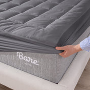 A corner of a mattress on a wood frame. A mattress pad is covering the mattress.