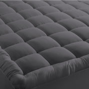 A mattress pad on a bed with 2 pillows on top