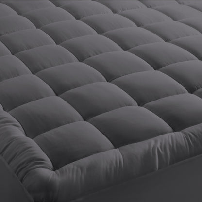 A mattress pad on a bed with 2 pillows on top