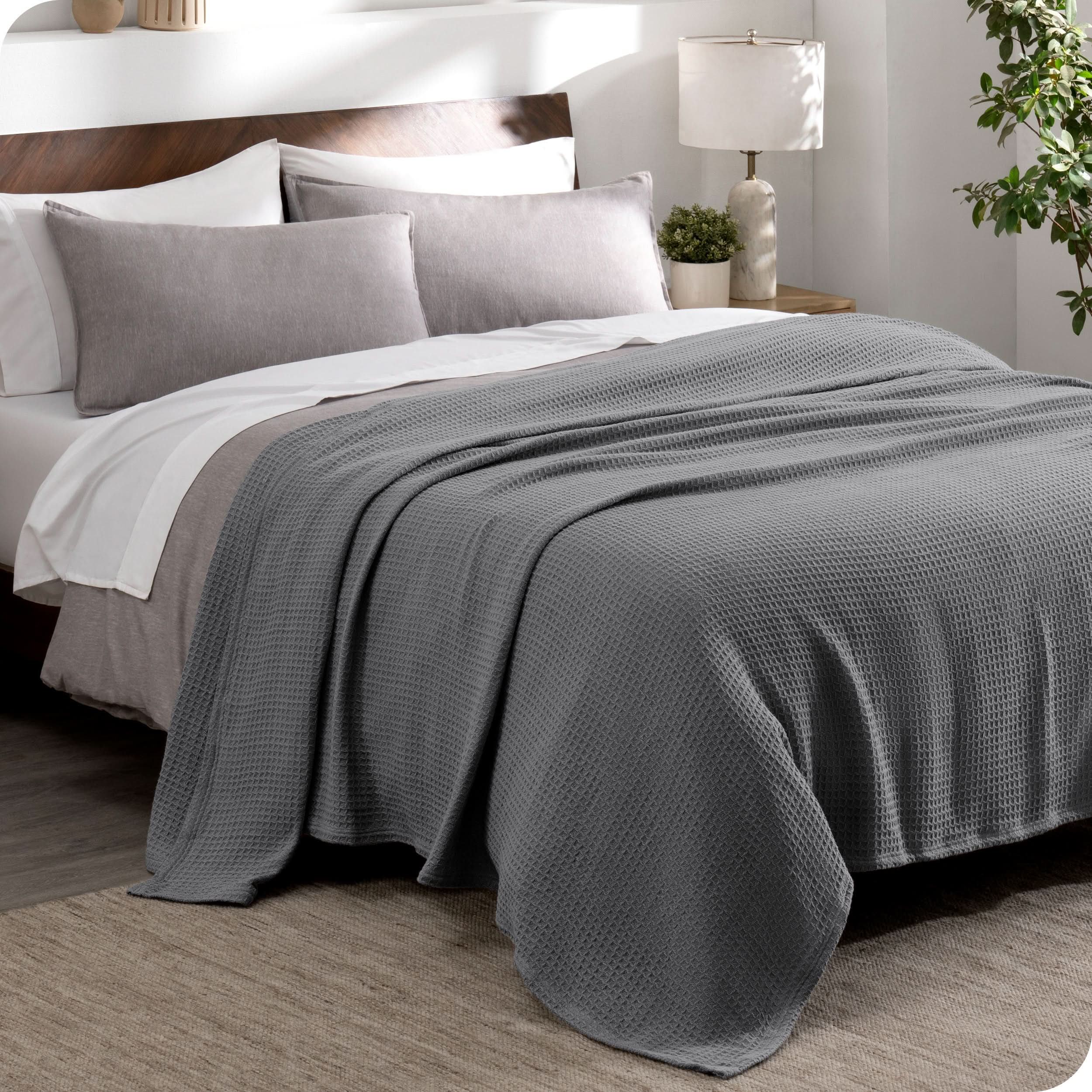 A cotton waffle blanket draped over the top of a bed made with a duvet set