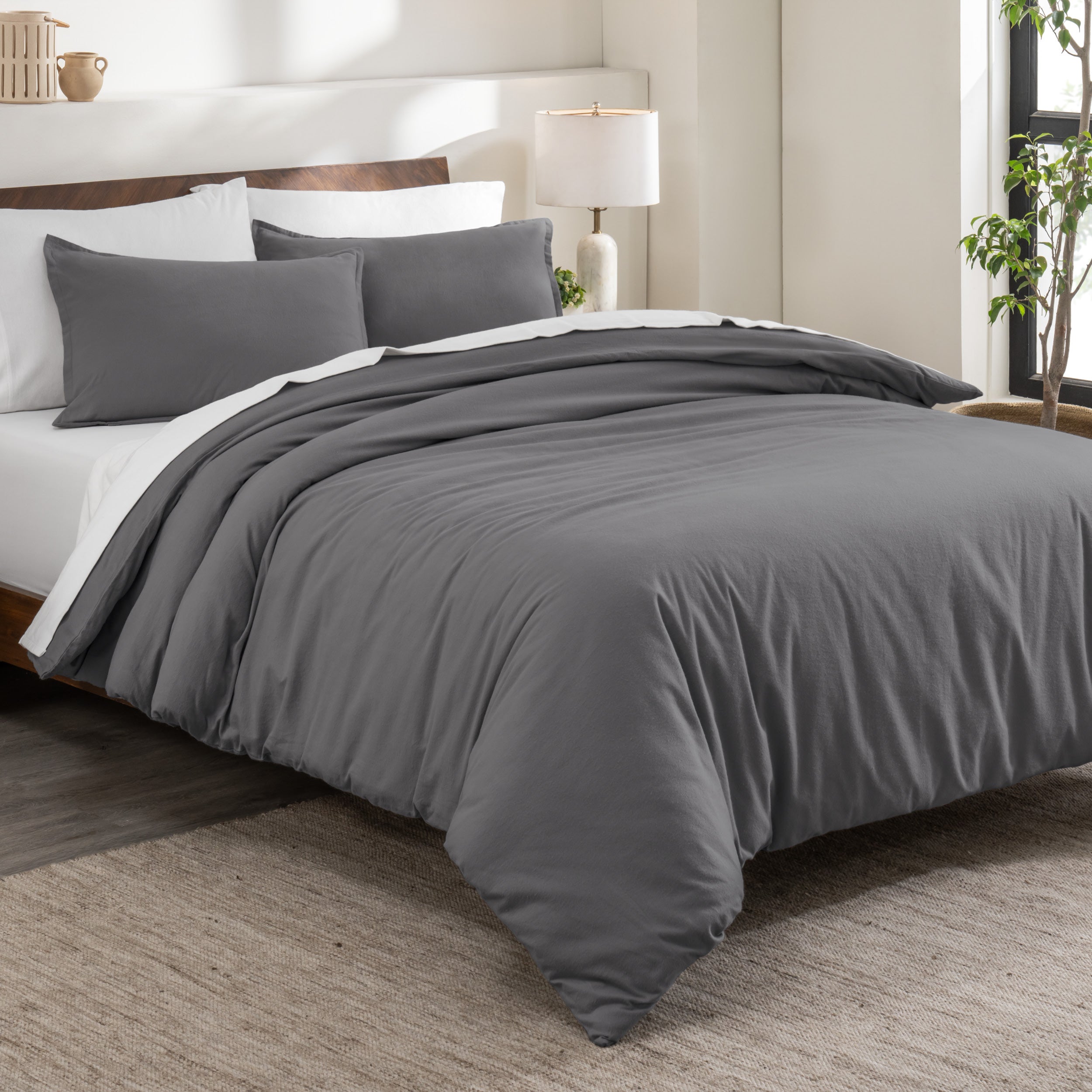 Flannel duvet cover set on a bed in a bedroom with a lamp and plant in the background.