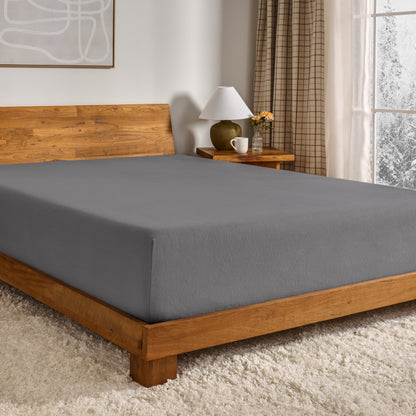 Grey fitted sheet on a wooden bed in a bedroom setting