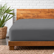 A modern bed with a wooden bed frame with a flannel fitted sheet on.