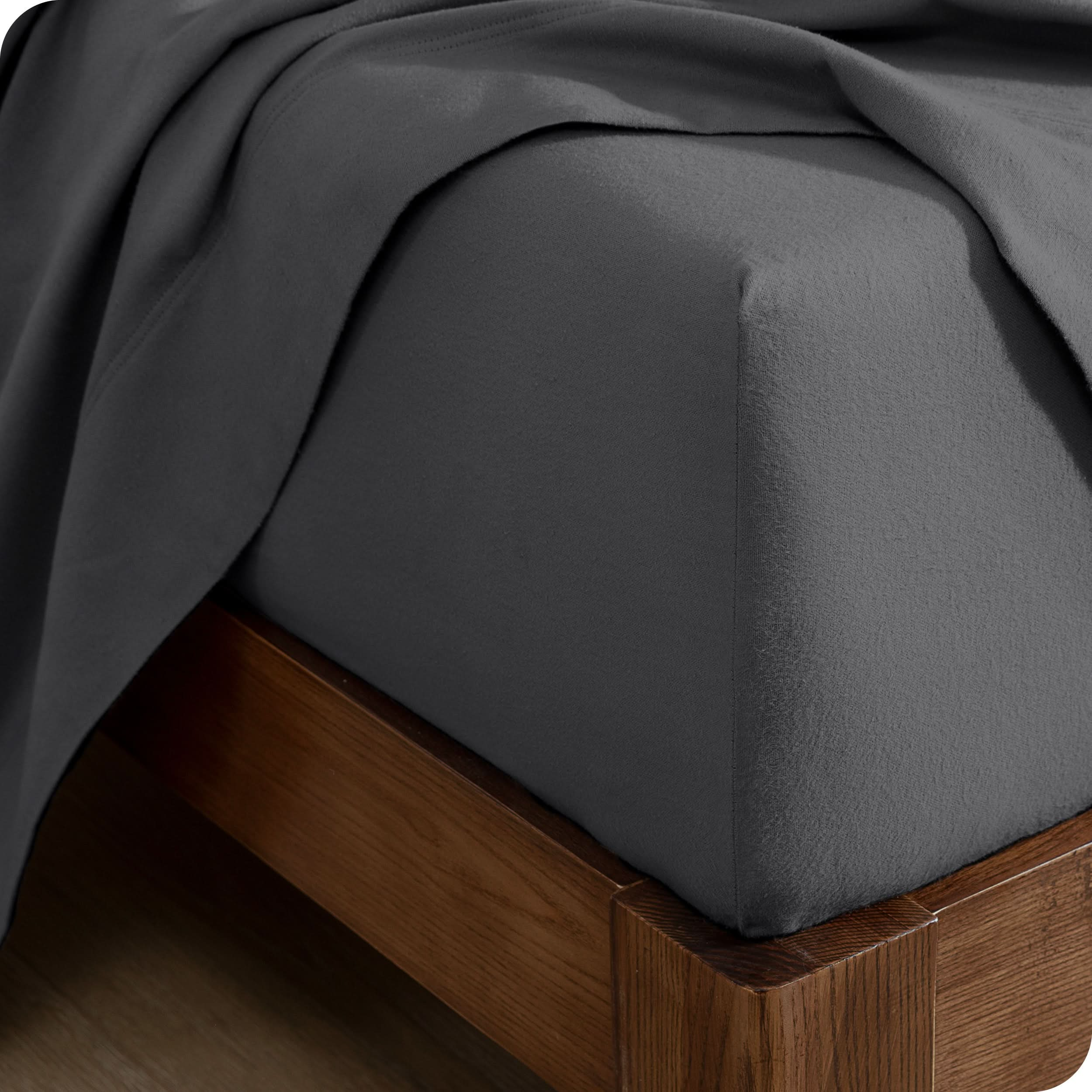 A close up of a corner of a modern bed with a flannel fitted sheet on.