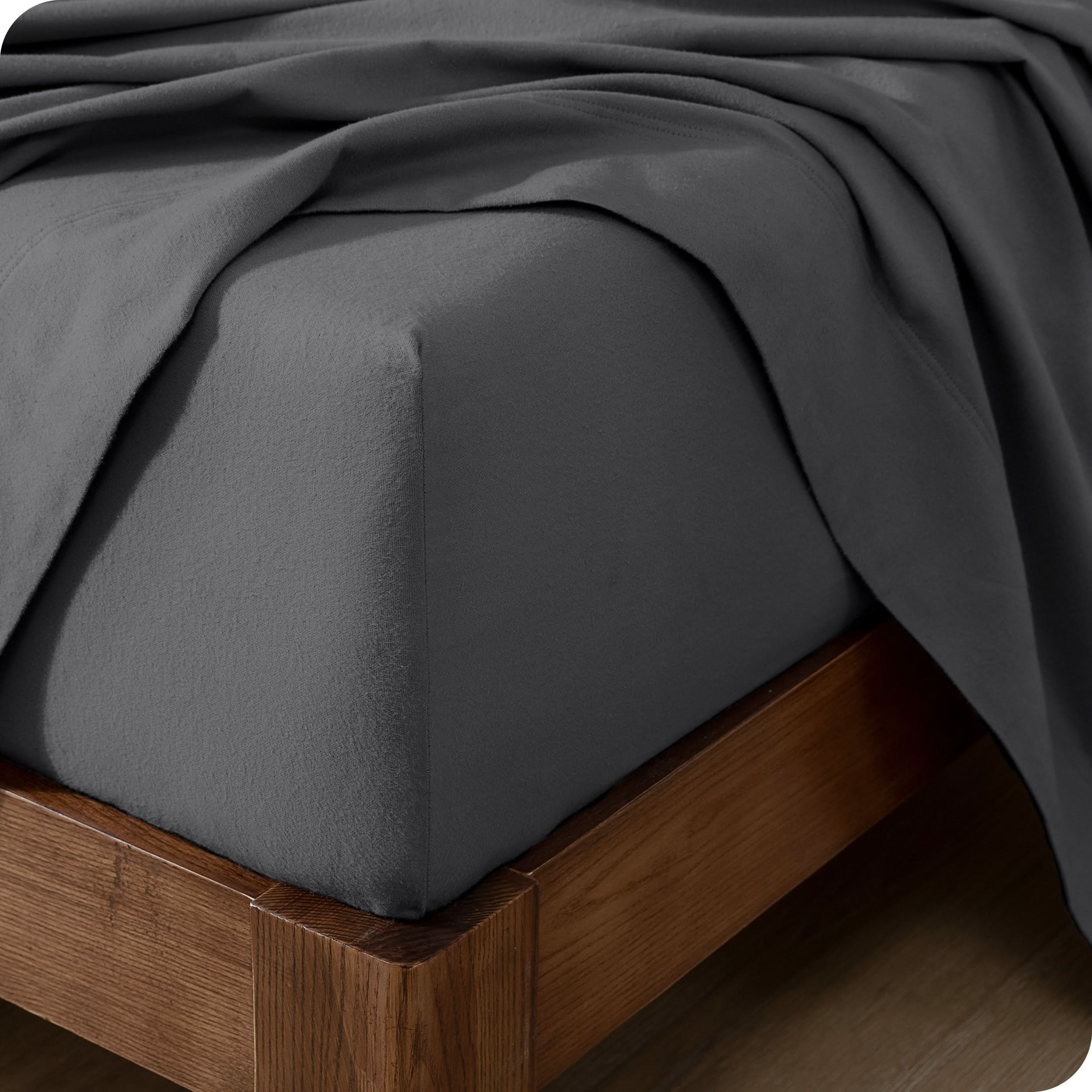 Close up of the corner of a mattress with a flannel fitted sheet and flat sheet on it