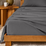 Bed with flannel bedding and wooden headboard and nightstand next to it.
