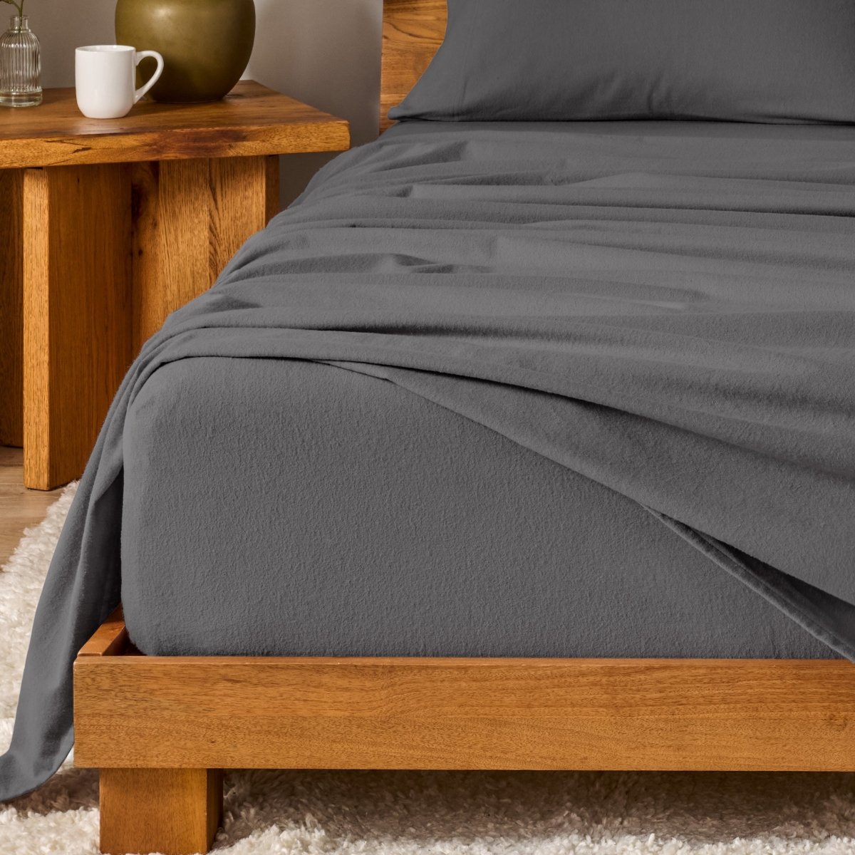Bed with flannel bedding and wooden headboard and nightstand next to it.