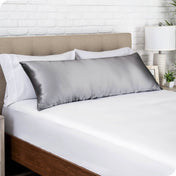 A silk body pillowcase on a pillow resting on a headboard