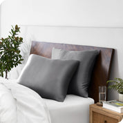 Two silk pillowcases over plush pillows, adorning a neatly made bed