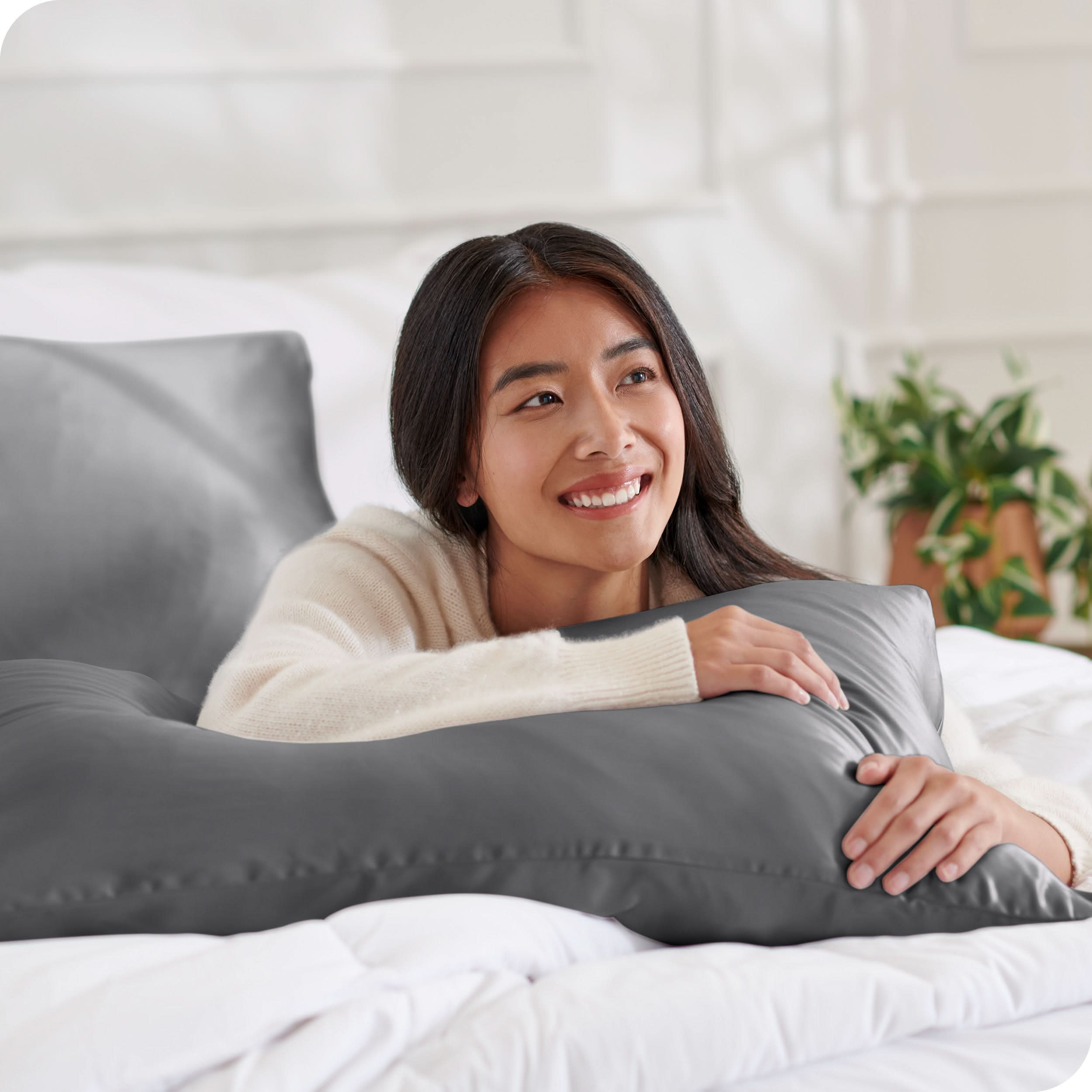 A woman on a bed with a silk pillowcase covered pillow