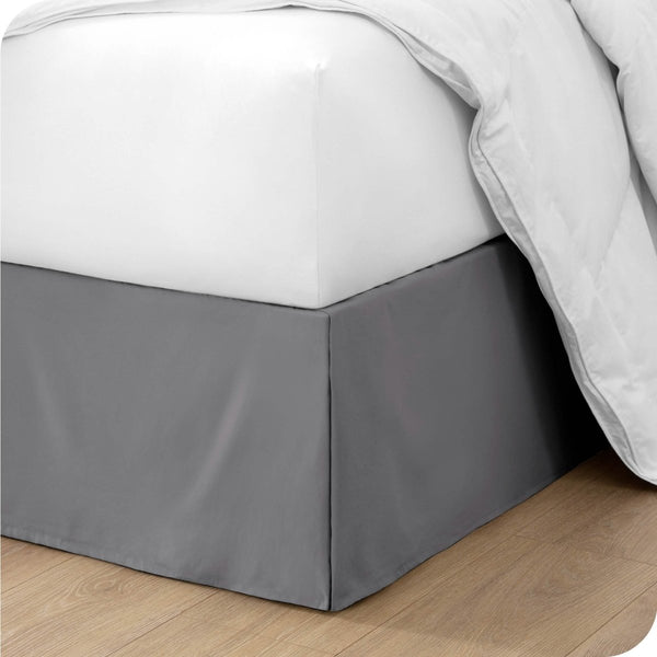The corner of a bed with a bed skirt and comforter on it