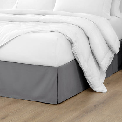 Microfiber bed skirt on a bed with white bedding and wooden floor.
