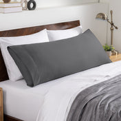 Bed sheets and pillows on a neatly made bed with a wooden headboard.